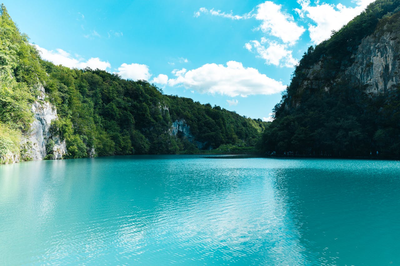Explore the serene turquoise waters surrounded by lush greenery and cliffs in Plitvice Lakes National Park, Croatia.